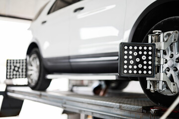 Modern car wheel undergoing alignment on lift in garage
