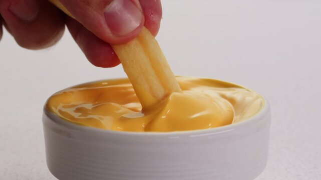 Curry cheese lemon sauce close up, fast food cafe Pouring fries potato and fry chicken in mayo yellow creamy cheese sauce close-up. Eat chicken nuggets with Peruvian sauce. Fast and junk food concept.