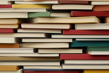 Close-up of stacked books in various colors with visible spines and pages. knowledge and education