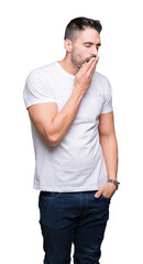 Fototapeta premium Young man wearing casual white t-shirt over isolated background bored yawning tired covering mouth with hand. Restless and sleepiness.