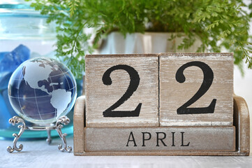 Earth Day - April 22 date on a wooden calendar with glass earth globe showing North and South America