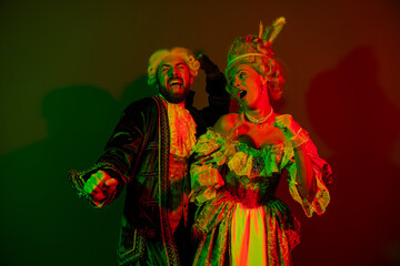 Fototapeta premium Elegant couple in colorful costumes enjoying a vibrant masquerade with historical theme lighting