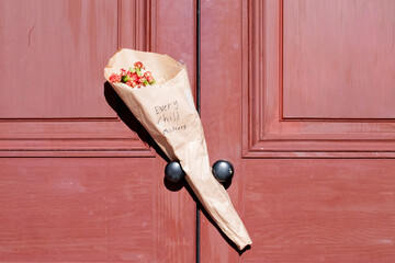 A bouquet of dainty colorful flowers wrapped in brown paper. There's a handwritten message on the...