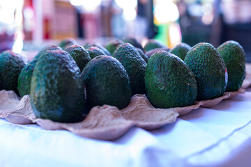 A cardboard fruit tray filled with large cultivated avocados. The greenish textured flesh of the...