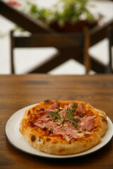 Delicious full ham pizza served on outdoor restaurant table, close-up food photography of Italian cuisine meal