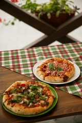Delicious pizza served on wooden table with green plaid tablecloth. Italian cuisine concept