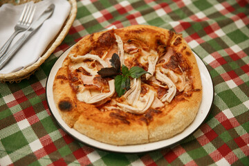 a delicious ham chicken pizza on tablecloth , sliced served on a wooden board with a backdrop of a burlap tablecloth