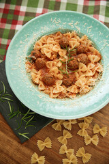 Macaroni pasta with meat pieces in tomato sauce and vegetables in bowl. Top view. Traditional Italian cuisine