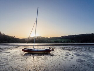 Sunrise over a catamaran resting on the mudflats. Peaceful morning scene. , Point Wells, Auckland,...