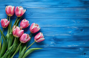 This captivating image features a bouquet of vibrant pink tulips arranged beautifully on a rustic blue wooden surface, creating a warm and inviting feel that captures the essence of springtime.