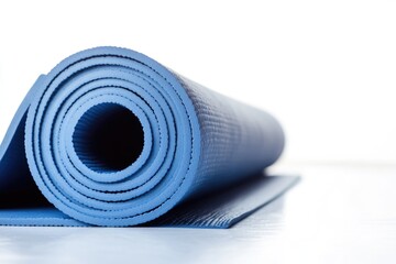 A blue yoga mat is rolled up on a white surface, perfect for storing or transporting