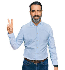 Middle aged man with beard wearing business shirt smiling looking to the camera showing fingers doing victory sign. number two.