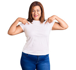Middle age latin woman wearing casual white tshirt looking confident with smile on face, pointing oneself with fingers proud and happy.