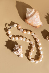 Necklace made of pink natural cultured pearls. Beads and seashells on beige background