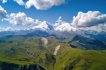 Fototapeta premium Majestic peaks rise above lush valleys under a vibrant blue sky adorned with fluffy clouds