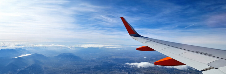 View through the window of a commercial airplane flying over clouds blue
