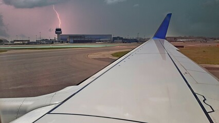 View of a commercial airplane wing with a storm before takeoff