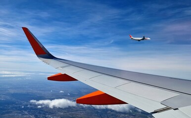 view of another plane taking off next to the wing of a commercial aircraft