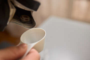 Pouring freshly ground coffee beans into a measuring cup for a perfect morning brew