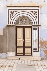 Kairouan, Tunisia. A brown door on a stucco building.
