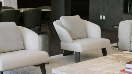 Modern living room with dark walls furnished with white design armchairs, soft couch and marble table. Luxury details in private villa