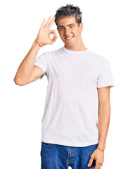 Young handsome man wearing casual white tshirt smiling positive doing ok sign with hand and fingers. successful expression.