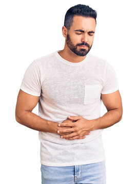 Young hispanic man wearing casual clothes with hand on stomach because indigestion, painful illness feeling unwell. ache concept.