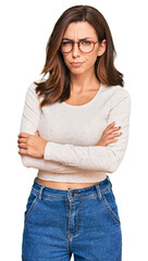 Young brunette woman wearing casual clothes and glasses skeptic and nervous, disapproving...