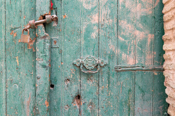 Sidi Bouzid, Tunisia. Padlock on a weathered green wooden door.