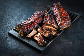 Charcoal smoked barbecue spareribs St Louis cut with hot rub and BBQ sauce served as close-up on an old rustic grillage