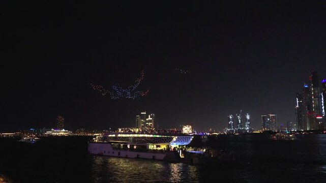 Drone show in night sky over Bluewaters and JBR Beach promoting Dubai Shopping Festival. People from pleasure yachts watch show. Taken from hands. High quality 4k footage