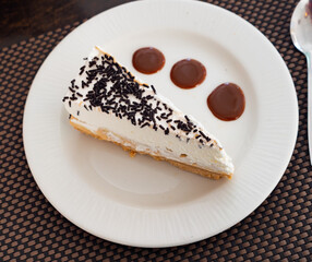 Delicious slice of banoffee pie topped with whipped cream and chocolate sprinkles, perfect for dessert