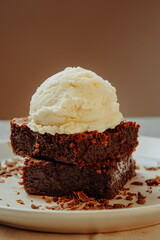 brownie com sorvete de creme em prato branco e fundo escuro