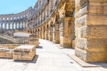Visitors stroll through the ancient Roman amphitheatre in Pula, Istria Peninsula, Croatia, admiring its stunning architecture and historical significance under a clear blue sky.