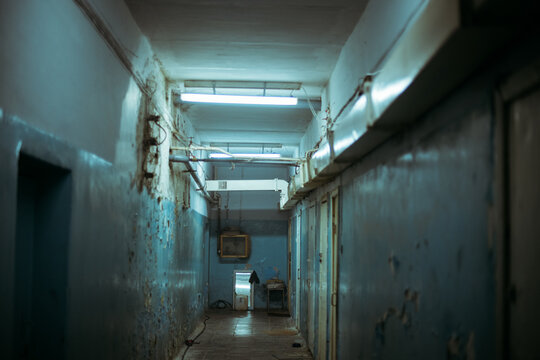 A scary, dark, mysterious corridor in an abandoned building with dim lights and peeling walls