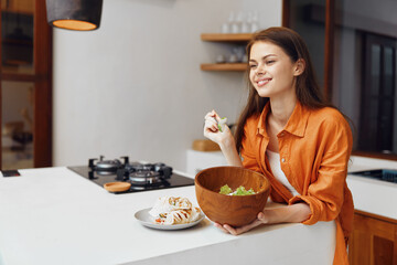 Young woman enjoying a fresh salad in a modern kitchen, showcasing healthy eating habits and a cheerful atmosphere