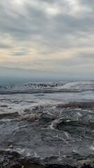 Travertine terraces of Pamukkale, Turkey, with a moody overcast sky and distant tourists