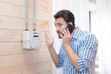 A worried man takes readings from his gas meter and tries to identify the problem during the energy crisis	