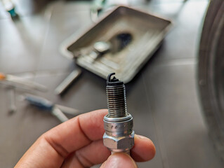 Close up of Man hand holds motorcycle spark plug. worker hands checking spark plugs motorcycle...