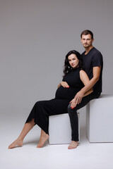 Obraz premium Expectant couple sharing a tender moment in a minimalist studio setting