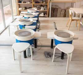 Empty potter's wheels with stools in a creative studio. Workstation for ceramics and clay