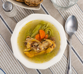 Hot and hearty soup is traditional Russian dish in plate. Chicken broth with long green noodles, decorated with carrot slices