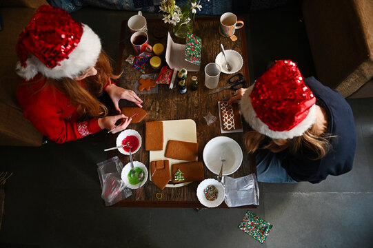 Two girls make a gingerbread house together