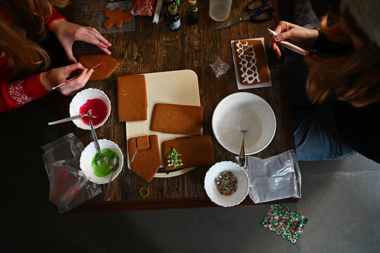 Two girls make a gingerbread house together