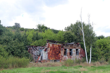 Ruins of a weathered village house surrounded by lush greenery in an abandoned landscape
