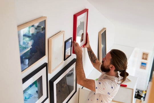 Man hangs framed pictures on the wall