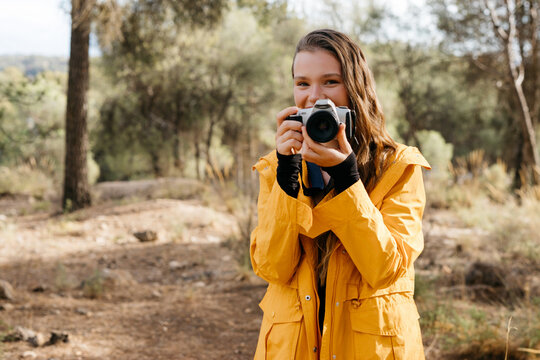 Female taking photo on camera in forest