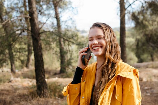 Smiling woman talking on smartphone in forest