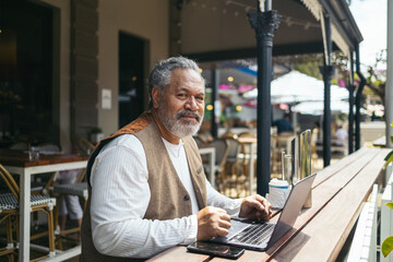 Senior man working with laptop in a restaurant