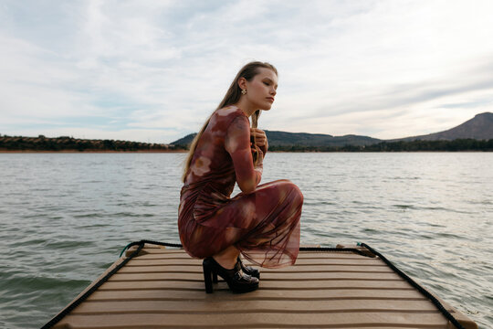 Thoughtful woman sitting on wooden pier